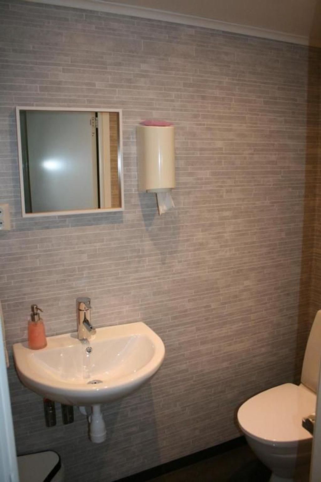 Een badkamer met een wit wastafel, een spiegel en een toilet.