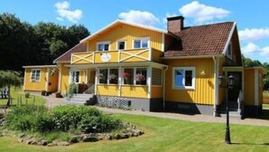 Un bâtiment jaune avec un porche, une cheminée et un petit jardin.
