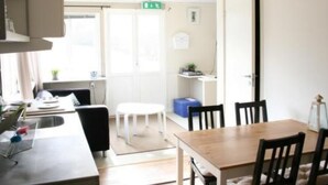 Une cuisine moderne avec un coin repas, comprenant une table et des chaises en bois, un évier et une fenêtre laissant entrer la lumière naturelle.