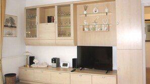 Ein Wohnzimmer mit Fernseher, Schränken und Regalen mit Dekoration.