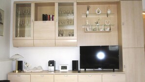 Ein Wohnzimmer mit Fernseher, Schränken und Regalen.