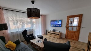 A living room with a sofa, chairs, a coffee table, a TV, and a wooden cabinet. - Gemütliches Ferienhaus mit Garten und Terrasse by Interhome (Norden)