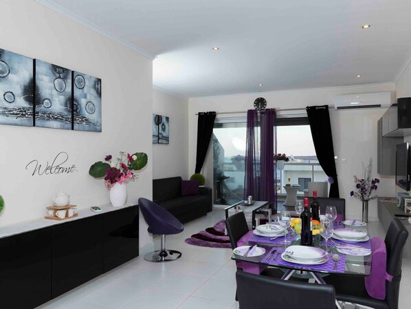 A modern dining area with a glass table set for six, surrounded by black and purple chairs. - Schöne, strandnahe Ferienwohnung in San Tumas by Interhome (Marsascala)