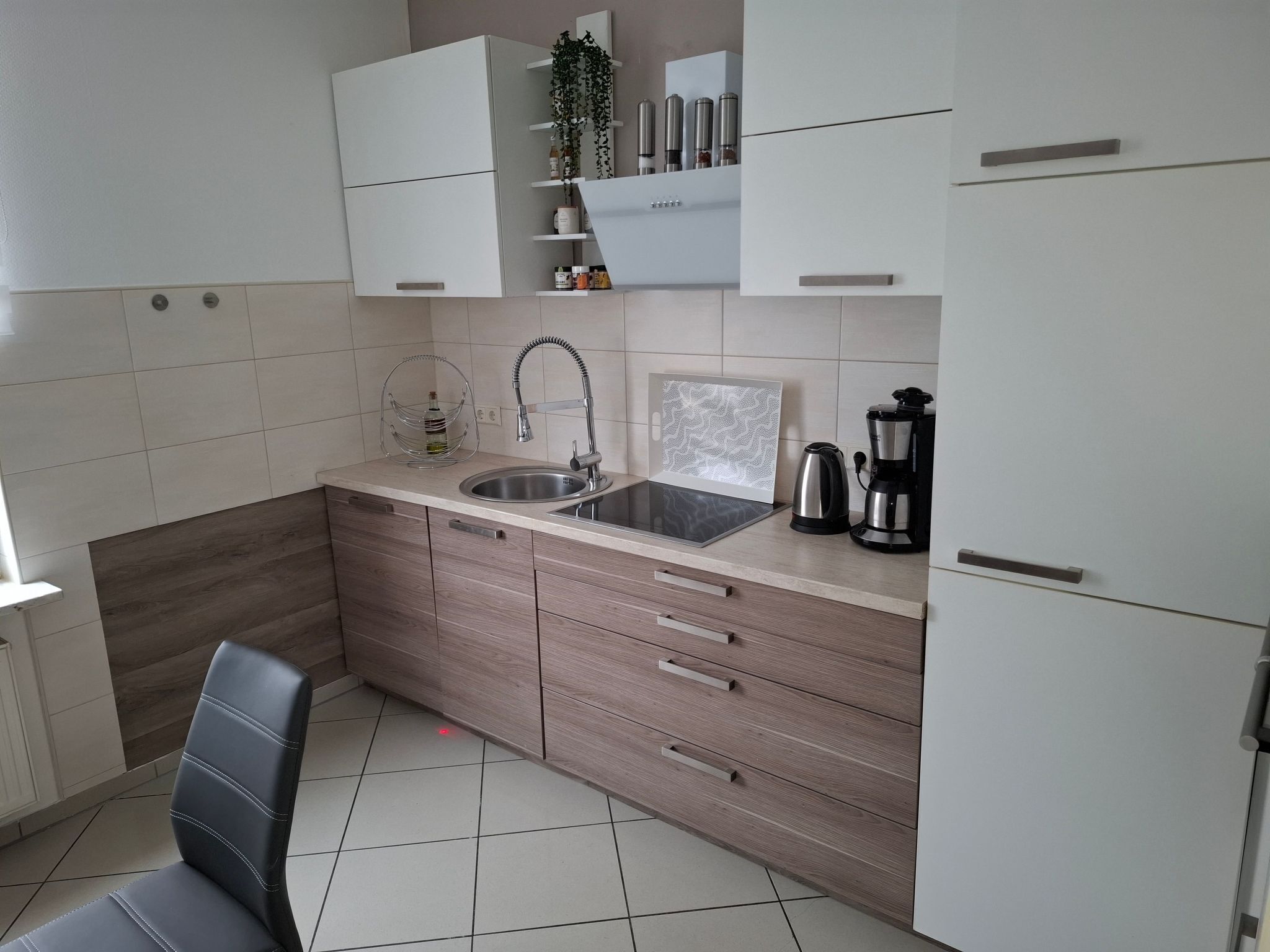 Una cocina moderna con un lavamanos, una cafetera y armarios.
