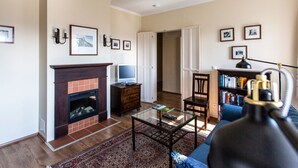 Una sala de estar con chimenea, televisor, estantería y mesa de centro.