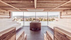 Un interior moderno con vigas de madera, una zona de estar central y un ventanal con vistas a la ciudad.