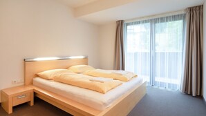 Ein Hotelzimmer mit Bett, Nachttisch und einem fenster mit Vorhängen.