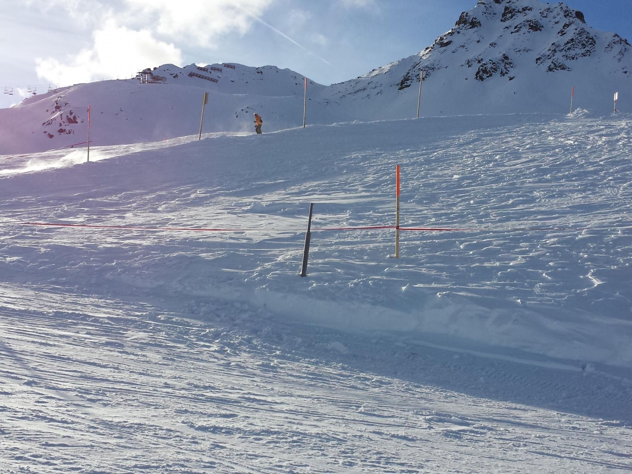 Ein verschneiter Skipisten mit Skiliften und einem Berg im Hintergrund.