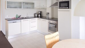 A modern kitchen with white cabinets, a stainless steel oven, a microwave, and a coffee maker. - Bohemia 2 in Gargellen by Interhome (Gargellen)