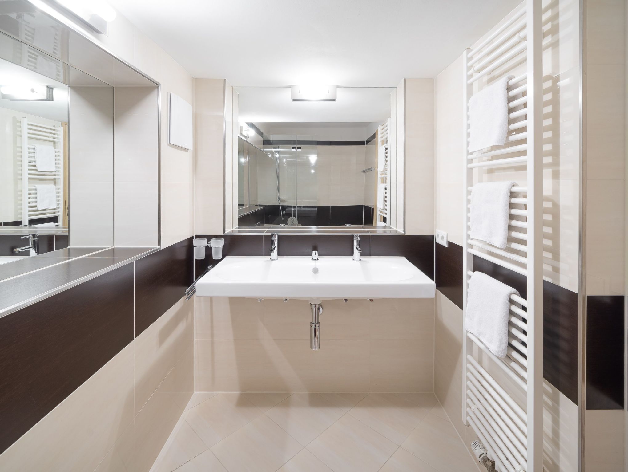 Un baño moderno con un lavamanos grande, un espejo y un perchero para toallas.