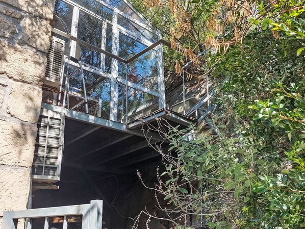 Un bâtiment en pierre avec un escalier métallique menant à un étage supérieur entièrement vitré.