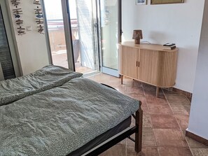 A room with a bed, a wooden cabinet, and a sliding glass door leading to an outdoor area. - Blue Elefant by Interhome (Agios Nikolaos)