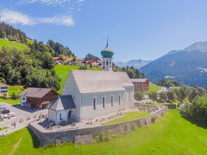 A church with a bell tower, surrounded by a stone wall and a small courtyard. - Wohnung in Sankt Gallenkirch mit Terrasse, Grill by Interhome (Schruns)