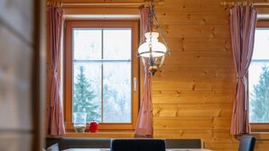 Een gezellig chaletinterieur met houten details, een tafel met stoelen en een hanglamp.