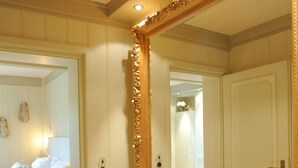 A bedroom with a large ornate mirror, a bed with white linens, and a door leading to another room. - Liiger Wal in Morsum by Interhome (Archsum)