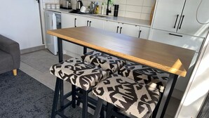 A kitchen with a wooden table and two bar stools with patterned cushions.