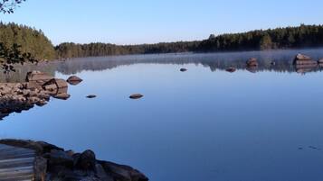 Un lago tranquilo con reflejos nítidos, rodeado de un área boscosa y costas rocosas.