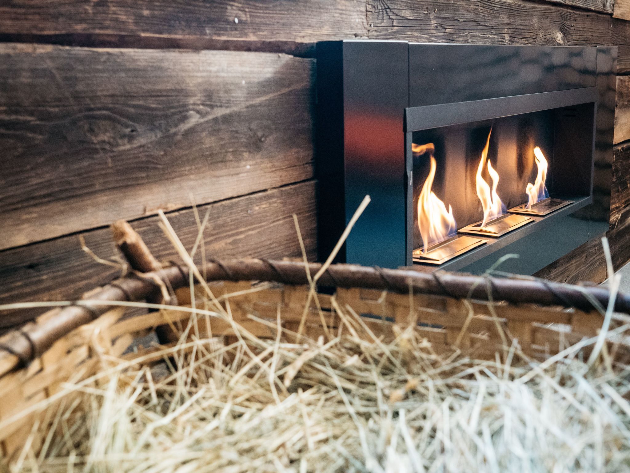Un camino moderno con tre fiamme ben visibili, incastonato in una parete di legno rustico.