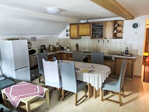 Una cocina compacta con comedor, armarios de madera, un refrigerador y un reloj en la pared.