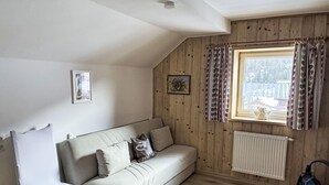 Una habitación acogedora con sofá, sillón, radiador y ventana con cortinas.