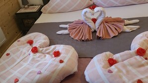 Una cama con ropa de cama a cuadros rosa y blanca, almohadas con forma de corazón y decoraciones de rosas.