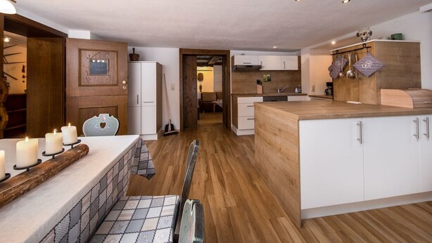 A modern kitchen with wooden flooring, white cabinets, and a central island. - Fewo Edelweiss by Interhome (Haller)