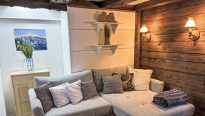 A modern living room with a sectional sofa, a small table, and a wooden wall with wall sconces. - Fewo Edelweiss by Interhome (Haller)