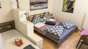 A bedroom with a bed, a nightstand, a chair, a small table, and a painting of a mountain. - Fewo Edelweiss by Interhome (Haller)