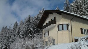 A two-story building with a sloped roof, surrounded by snow-covered trees and a clear sky. - in ruhiger Lage am Waldrand by Interhome (Navis)