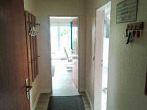 A hallway with a wooden door, a black mat, and a coat rack. - Körner Kornhof7 1.OG by Interhome (Dahme)