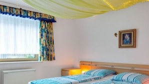 A bedroom with a bed, a nightstand, a lamp, and a window with curtains.