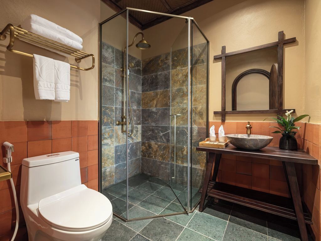 A bathroom with a glass-enclosed shower, a toilet, a sink with a basin, and a towel rack with towels.