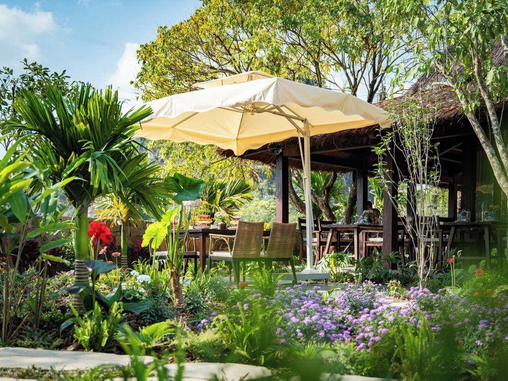 A garden with a wooden gazebo, a table with chairs, and a large umbrella.