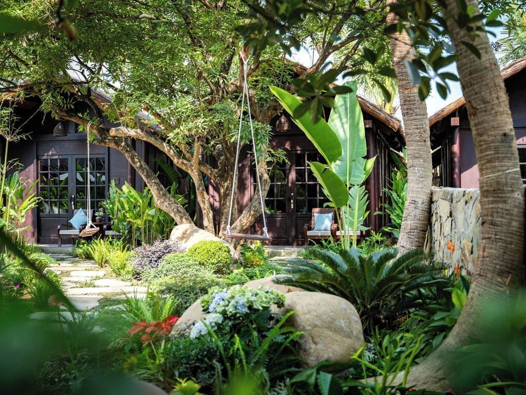 Un rigoglioso giardino con un edificio in legno, un'altalena e un vialetto in pietra.