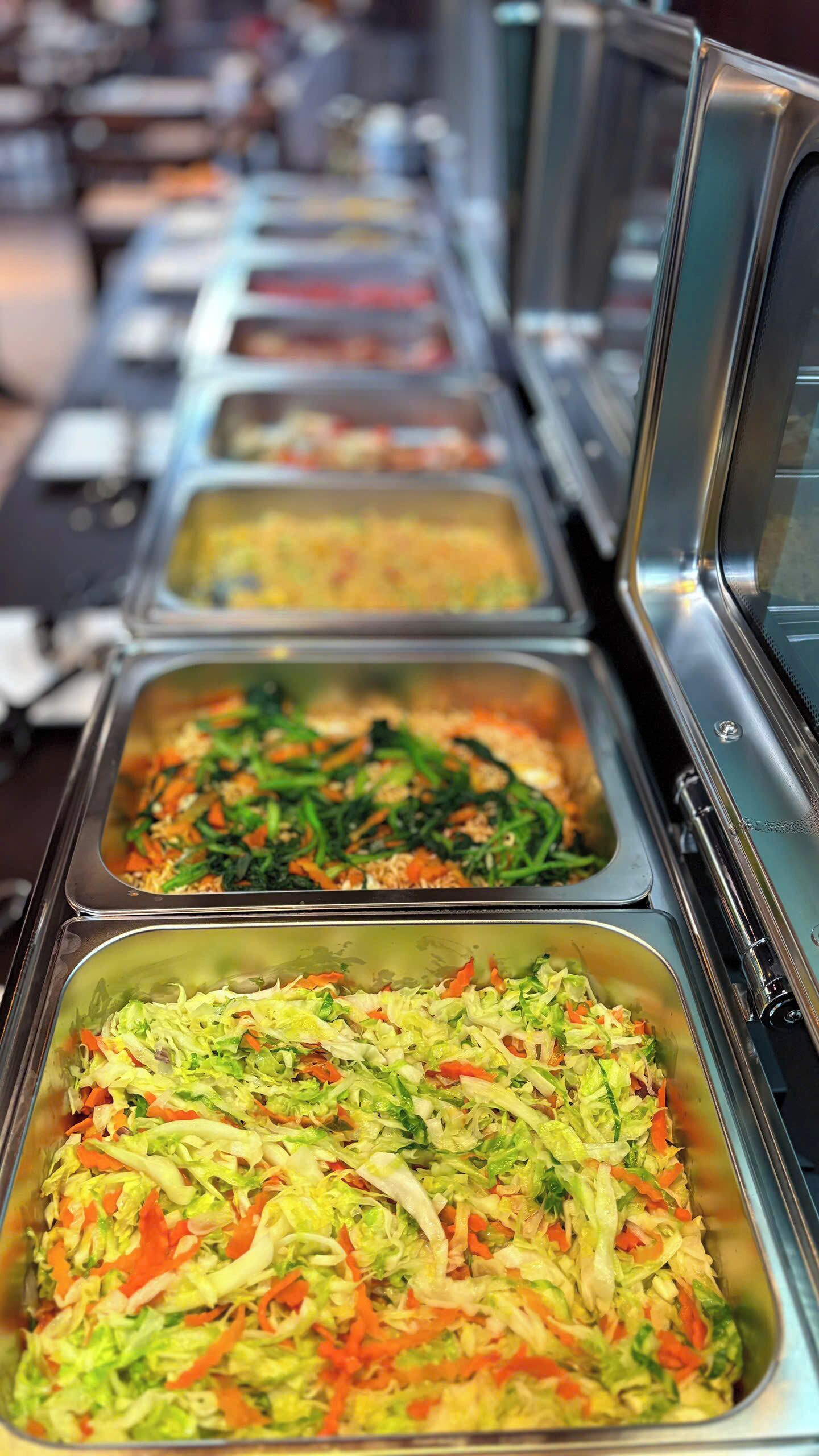 Una barra de buffet con diversas opciones de comida, incluyendo ensaladas y posiblemente otros platos.