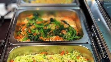 Una barra de buffet con diversas opciones de comida, incluyendo ensaladas y posiblemente otros platos.