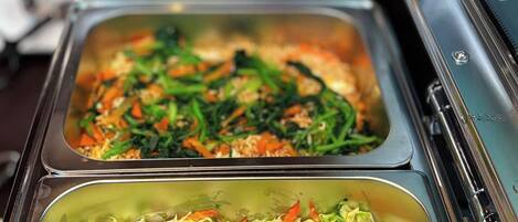 A buffet line with various food options, including salads and possibly other dishes.