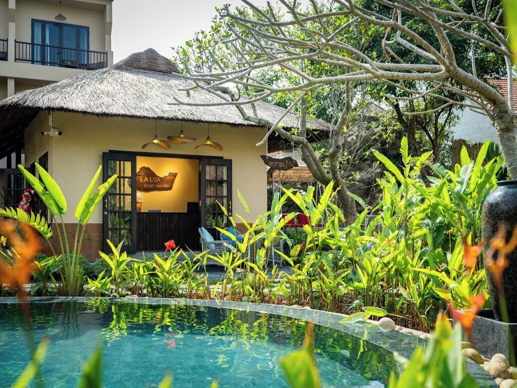 A resort with a pool, a reception area, and tropical plants.