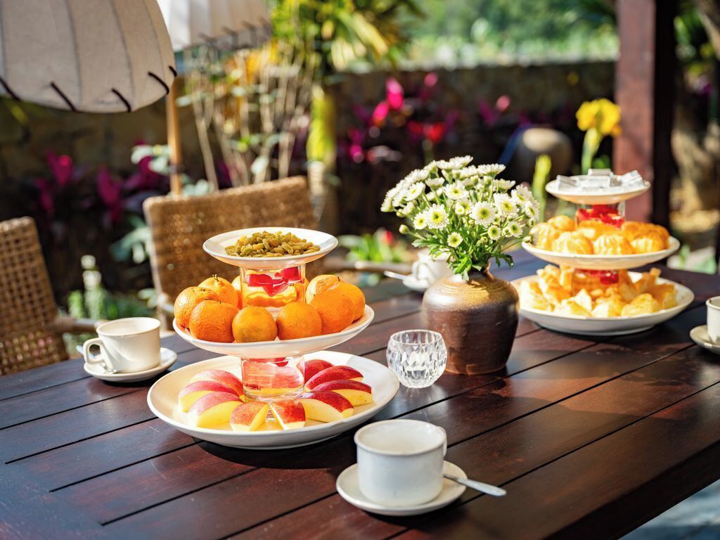 Una mesa de madera con diversos alimentos, como frutas, pasteles y un jarrón con flores.