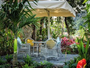 An outdoor patio with wicker furniture, a table, and a canopy. - La Lua Resort Ninh Binh (Tay Hoa Lu)
