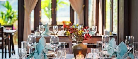 A dining table set with glassware, a vase with flowers, and a candle.