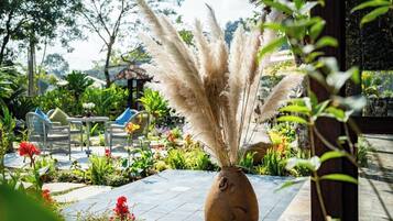 A patio area with a vase of pampas grass, outdoor furniture, and a variety of plants.