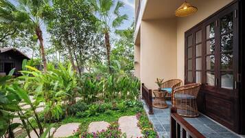 A balcony with a garden, wicker furniture, and a hanging light fixture.