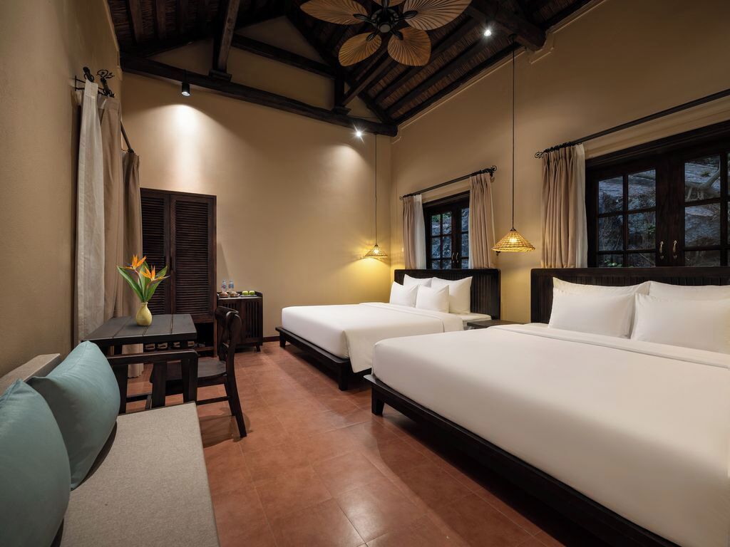 Habitación de hotel con dos camas, un escritorio y una silla.