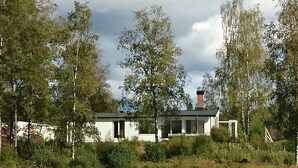 Una propiedad junto al lago con un edificio blanco, una chimenea y un muelle.