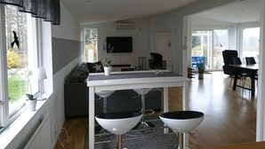 Una cocina moderna con una isla central, un comedor con mesa y sillas, y una sala de estar con sofá.