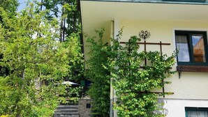 Een gebouw met twee verdiepingen, met een stenen trap die uitkomt op een houten terras.