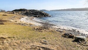 Un paysage côtier caractérisé par une côte rocheuse, des zones herbeuses et une vue dégagée sur l’eau.
