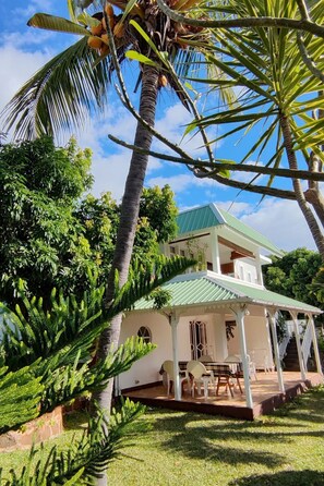 A two-story house with a green roof, surrounded by lush greenery and palm trees. - r garden Pointe aux sables by Interhome (Cap Malheureux)