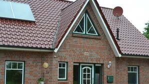 Un bâtiment en briques avec une porte verte, des fenêtres et une antenne parabolique.